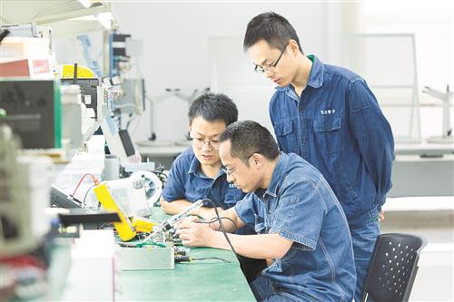 绵阳卷烟厂“张宝工作室”成员在修复成品物流电控系统的PLC功能模块